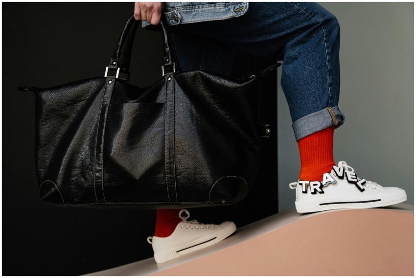 Close-up of person holding leather duffel bag with
