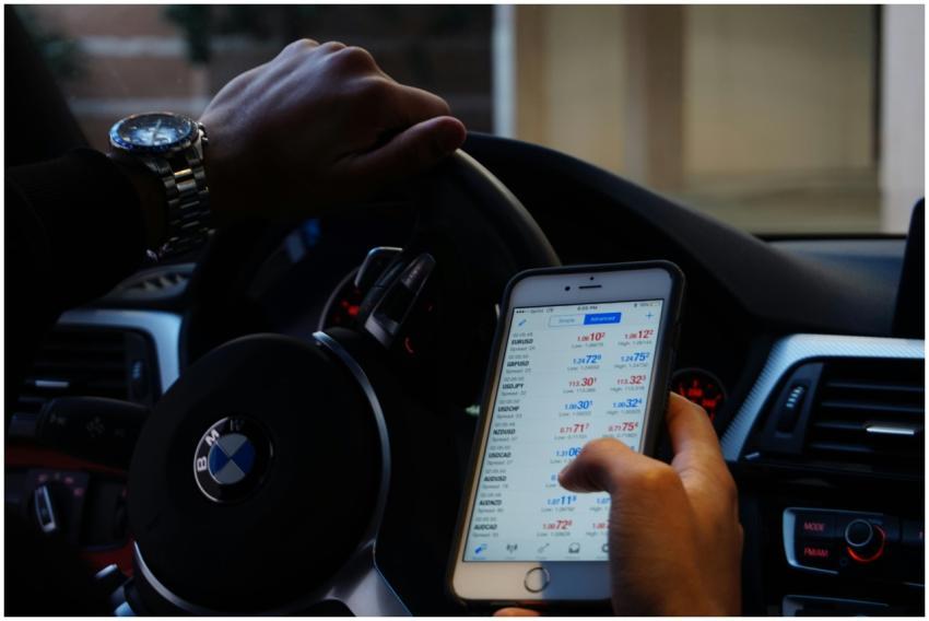 Person using mobile phone for currency trading whi