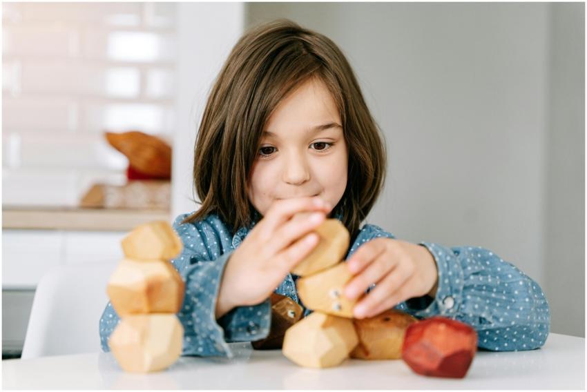 Child playing with wooden blocks indoors, focusing