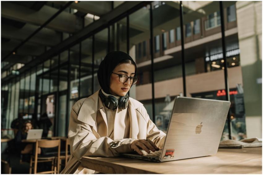 A focused woman wearing a headscarf works on her l