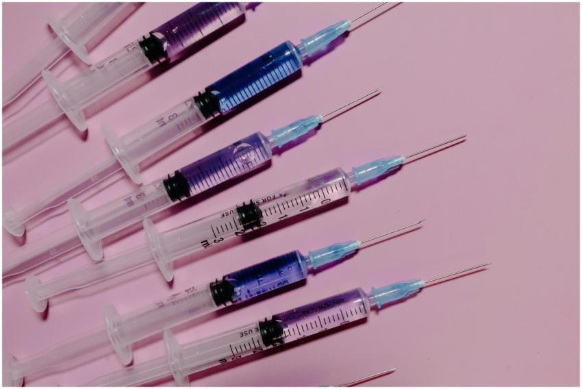 Several syringes with blue liquid on a pink backgr