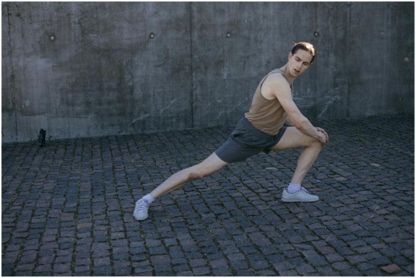 Young man performing a stretching exercise on a st