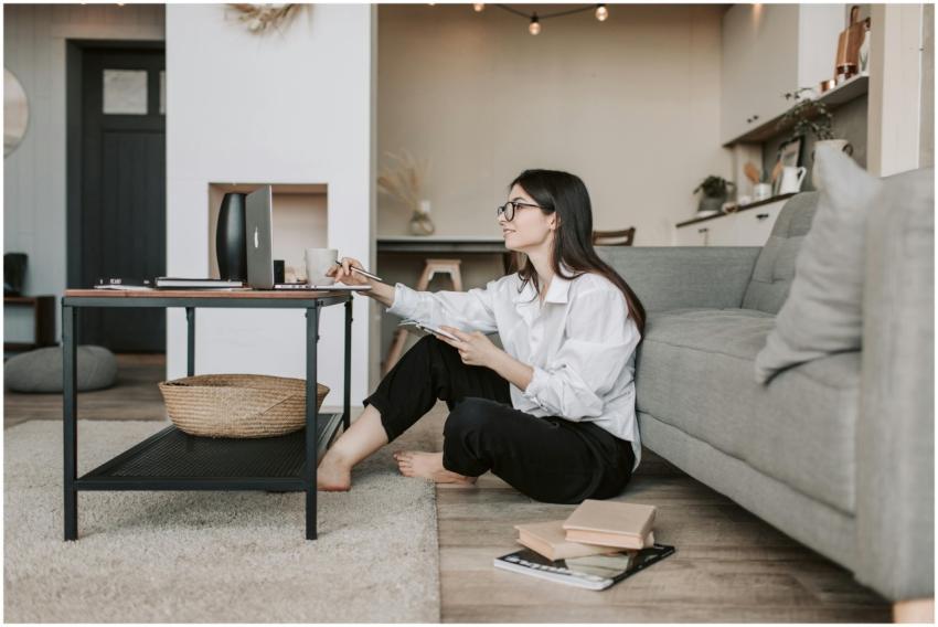 Woman using a laptop while sitting on the floor of