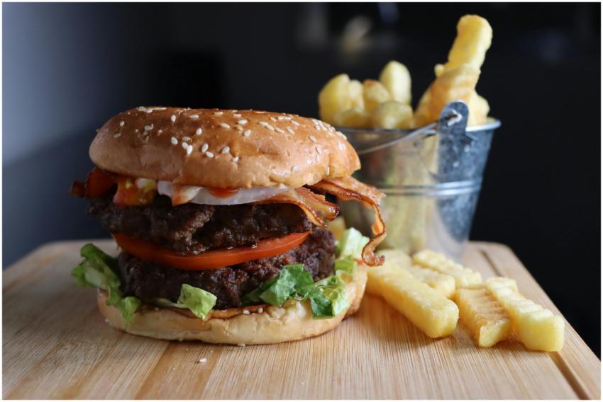 Mouthwatering burger with bacon, tomatoes, and fri