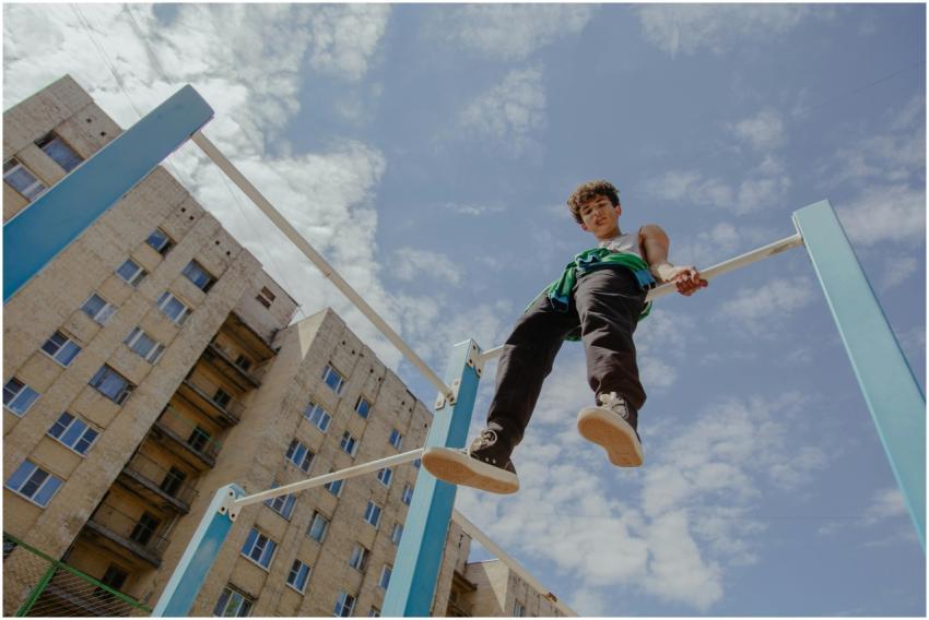 Teenager sitting on monkey bars in urban setting u