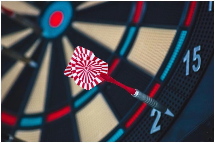A dart striking the bullseye on a dartboard, showc