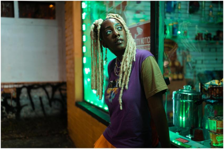 A fashionable woman with blonde locs posing at nig