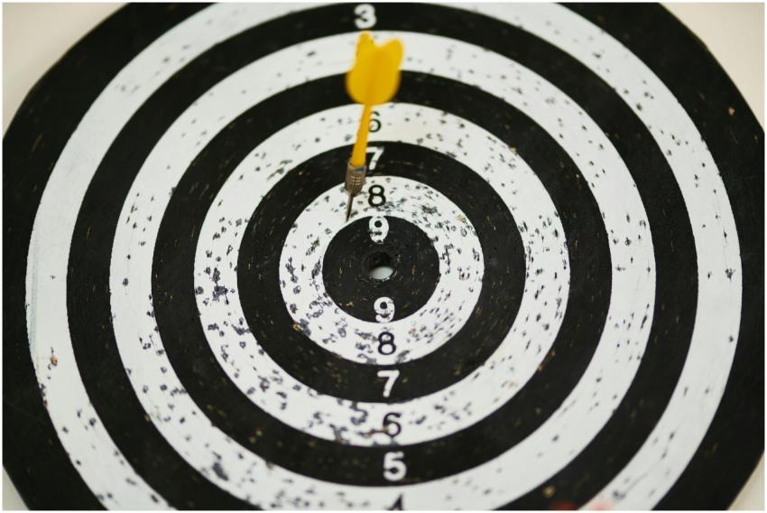 Close-up of a dart hitting the bullseye on a black