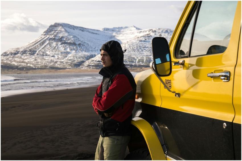 A person in warm clothing stands by a yellow truck