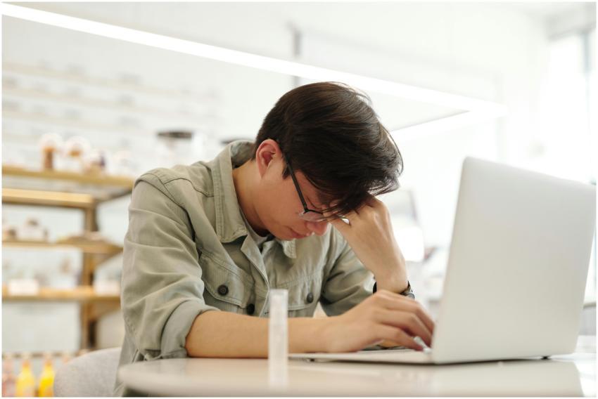 Exhausted young man working on a laptop inside a b
