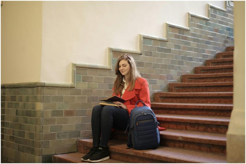 A young woman sitting and reading on an indoor sta