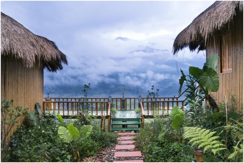 Bamboo huts overlooking lush gardens and misty mou