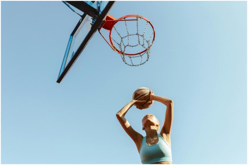 A young woman plays basketball outdoors on a sunny