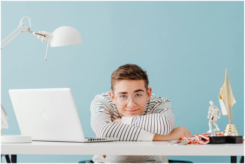 Young man with glasses leaning on a desk with a la