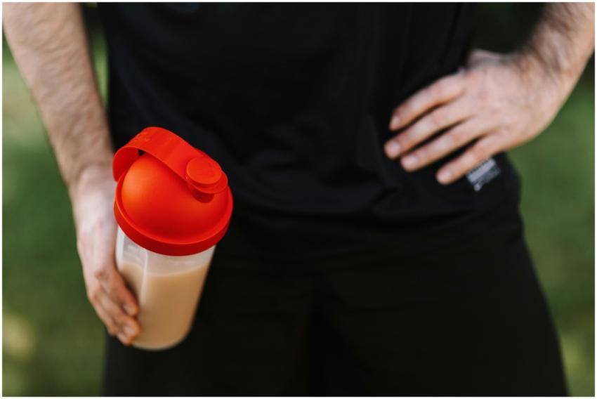 Close-up of a man holding a protein shake tumbler