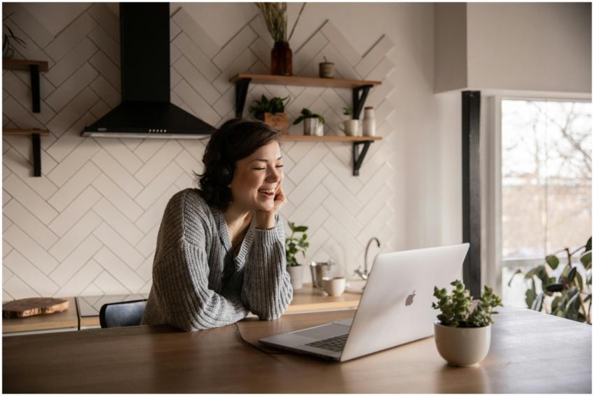 Young cheerful female smiling and talking via lapt