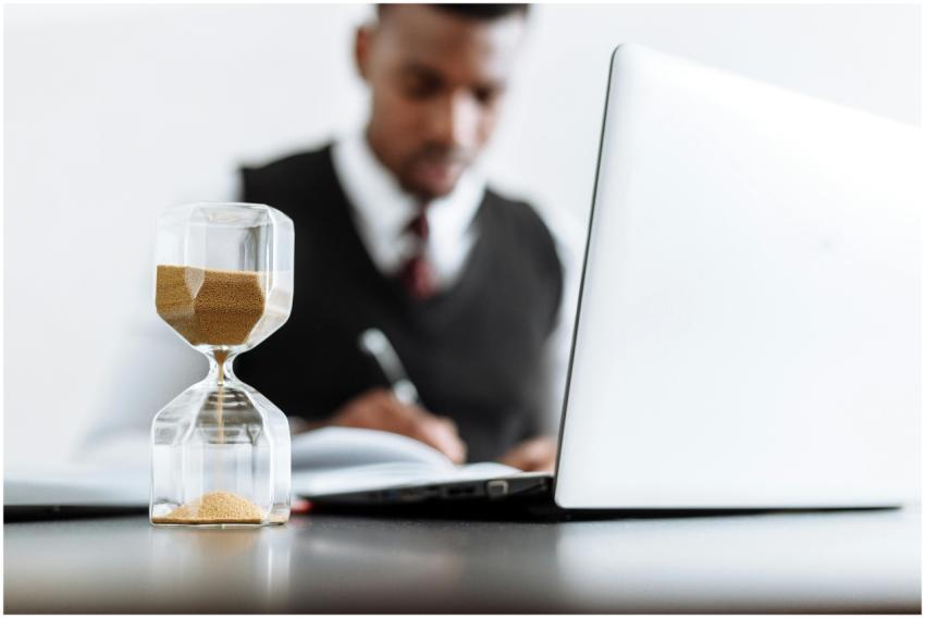 Businessman at desk with hourglass indicating time