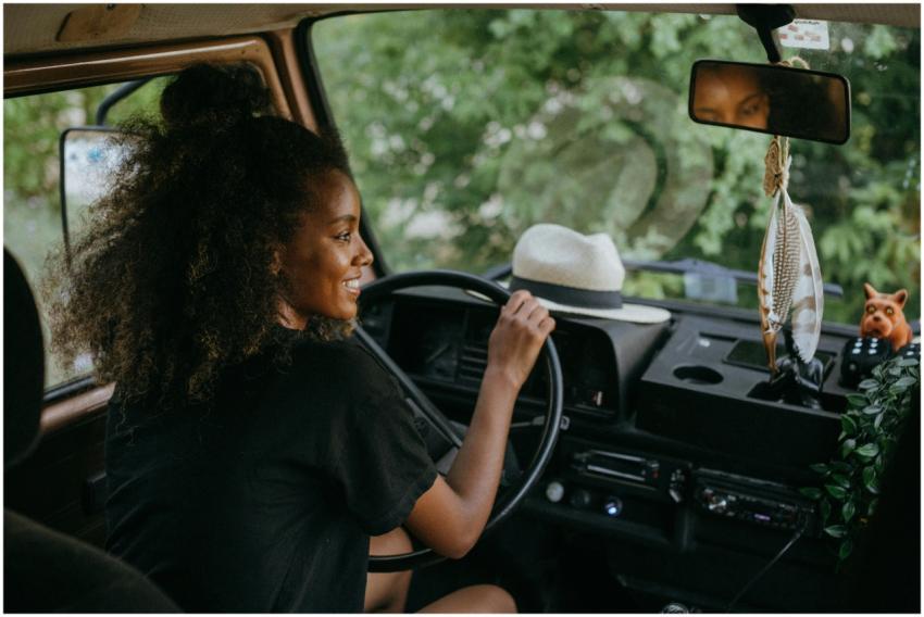 Woman driving a van through nature, enjoying a sum