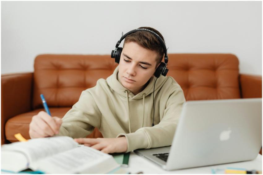 Teenage boy with headphones, focused on studying,