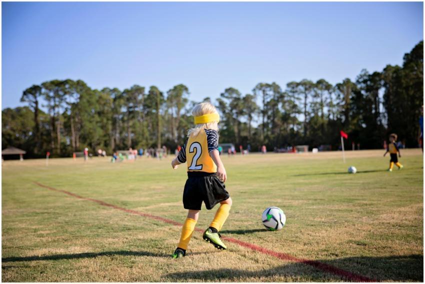 A young soccer player dribbles the ball on a sunny