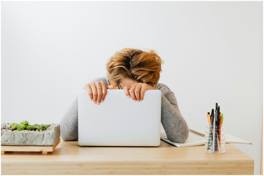 Woman wearing gray sleeves, leaning on laptop with