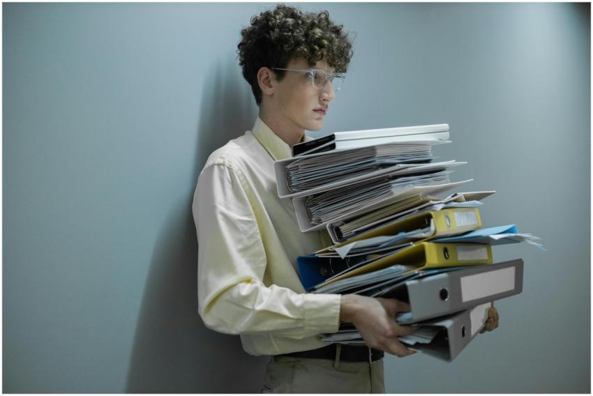 An overworked office worker carrying a large stack
