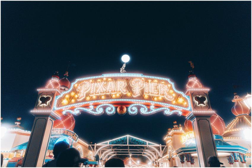 Brightly lit entrance to Pixar Pier at night, show