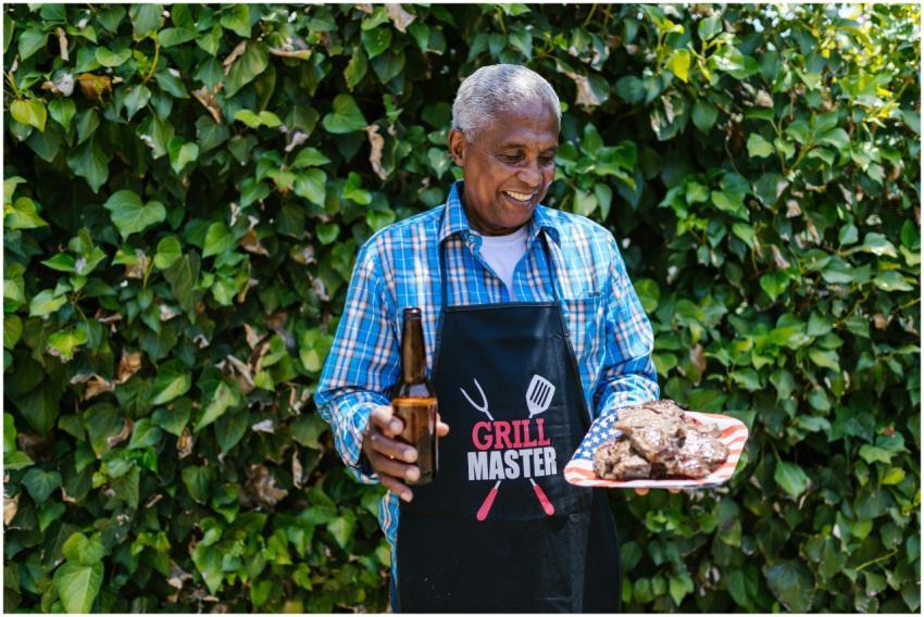 Elderly man holding grilled meat and beer, celebra