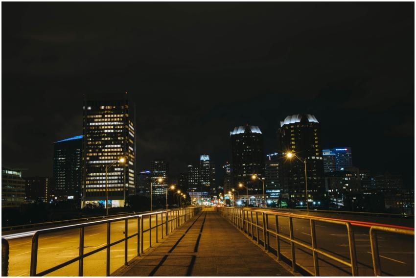 A pathway leading to a bustling city skyline illum