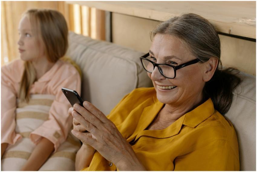Senior woman in glasses smiling while using smartp