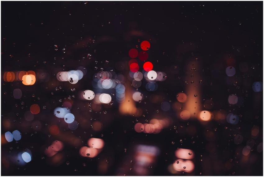Bokeh city lights and raindrops on glass create a