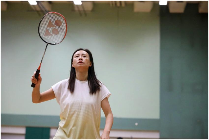Woman playing badminton indoors, showcasing focus