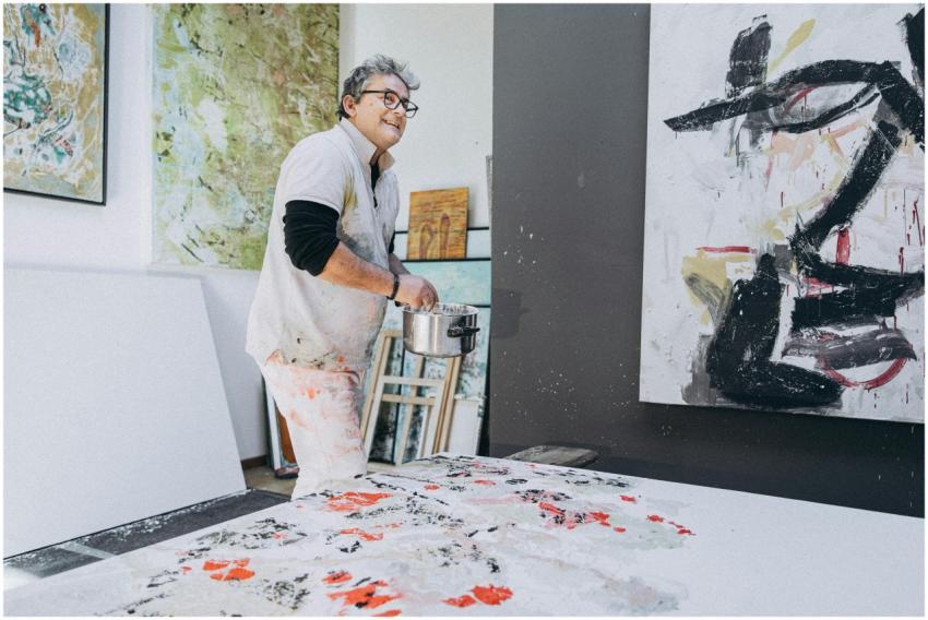 An artist joyfully creating a large abstract paint