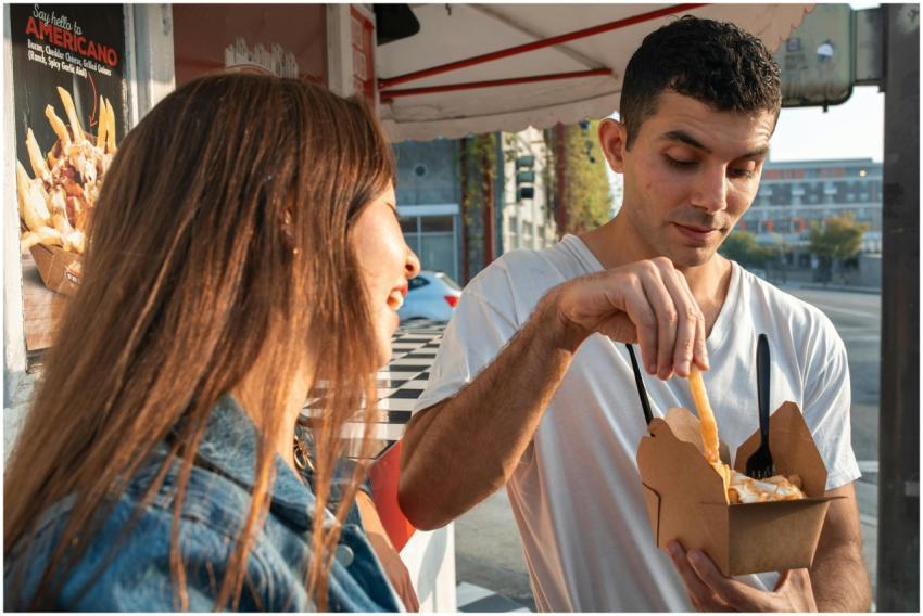 Two young adults savoring fries from a food truck