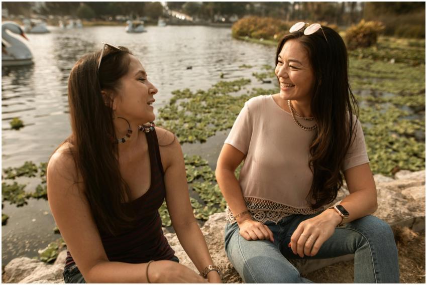 Two women sitting and smiling by the lake, enjoyin