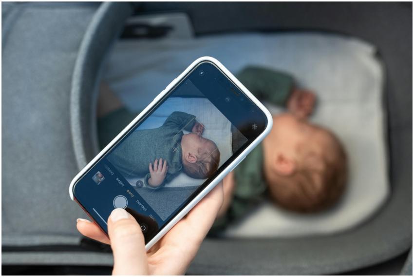A smartphone capturing a peaceful newborn baby sle