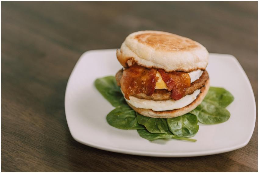 Tasty bacon and egg sandwich on a plate with fresh