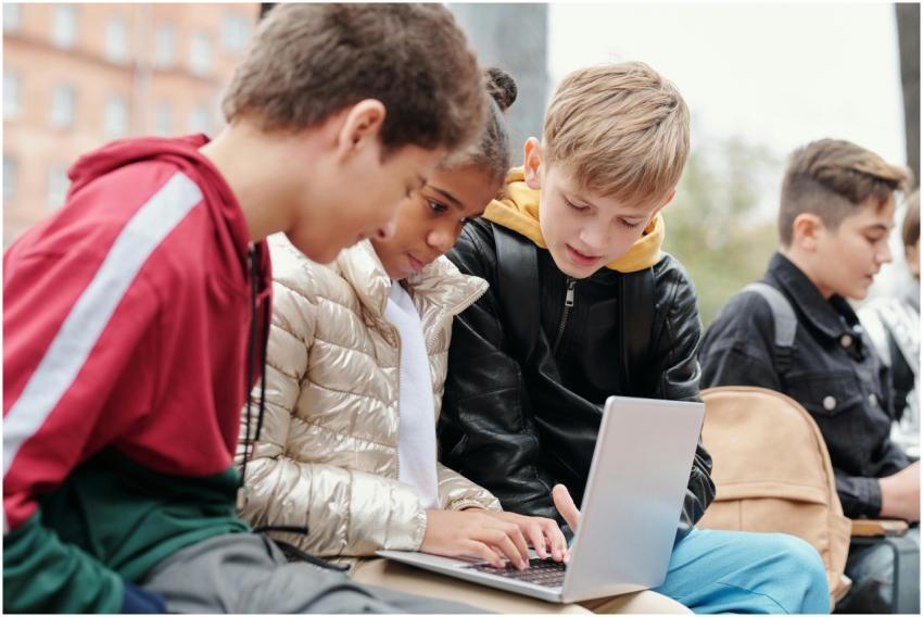 Group of teenagers studying together on a laptop o