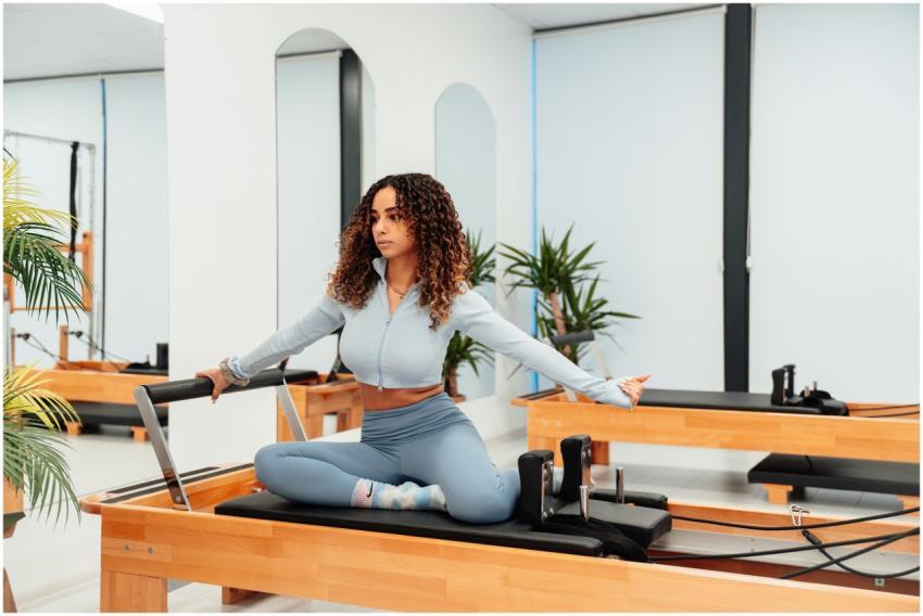 A woman performs pilates on a reformer machine in