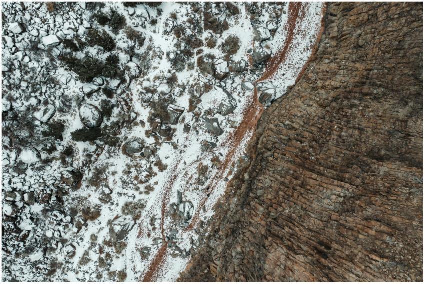 Aerial view of snowy landscape with rocks and tree
