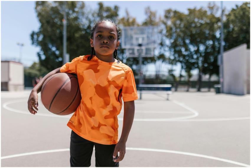 Confident child holding a basketball on an outdoor