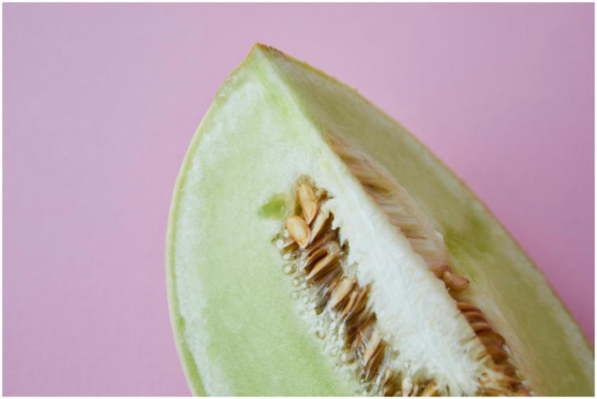 A close-up of a fresh honeydew melon slice with se