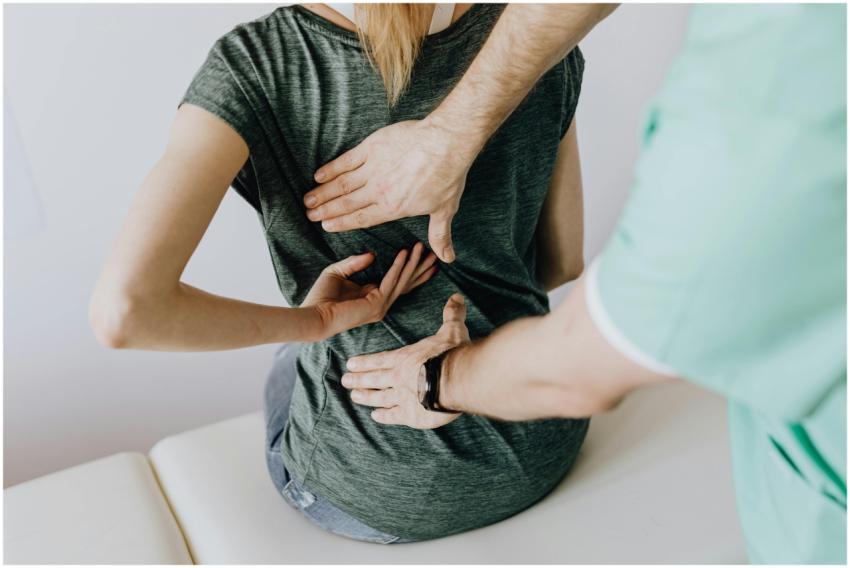 A chiropractor examining a patient's back to allev