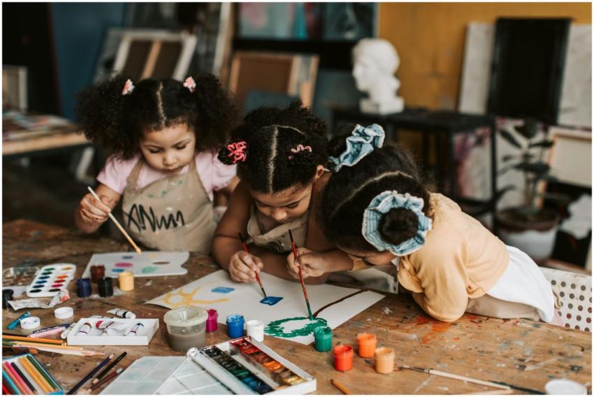 Three young girls engrossed in a painting activity