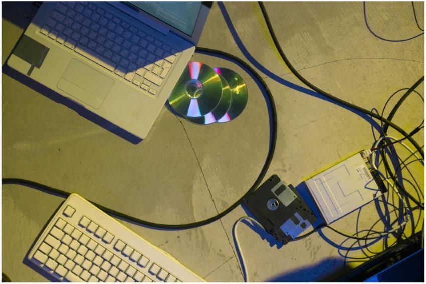 Flat lay of vintage laptop, CDs, floppy disk, and