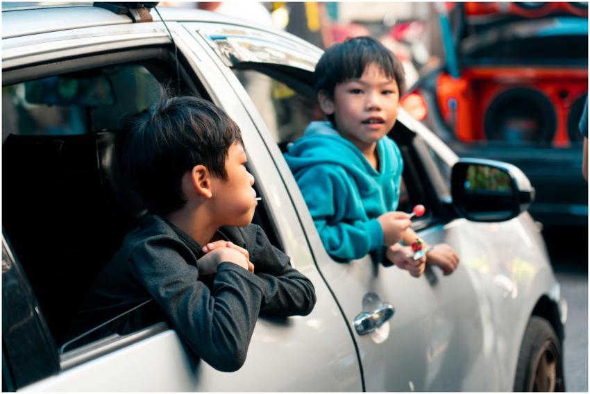 Two children looking out from a car window playful