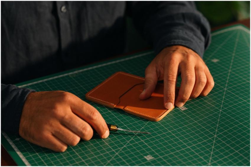Close-up of hands crafting a leather wallet on a g