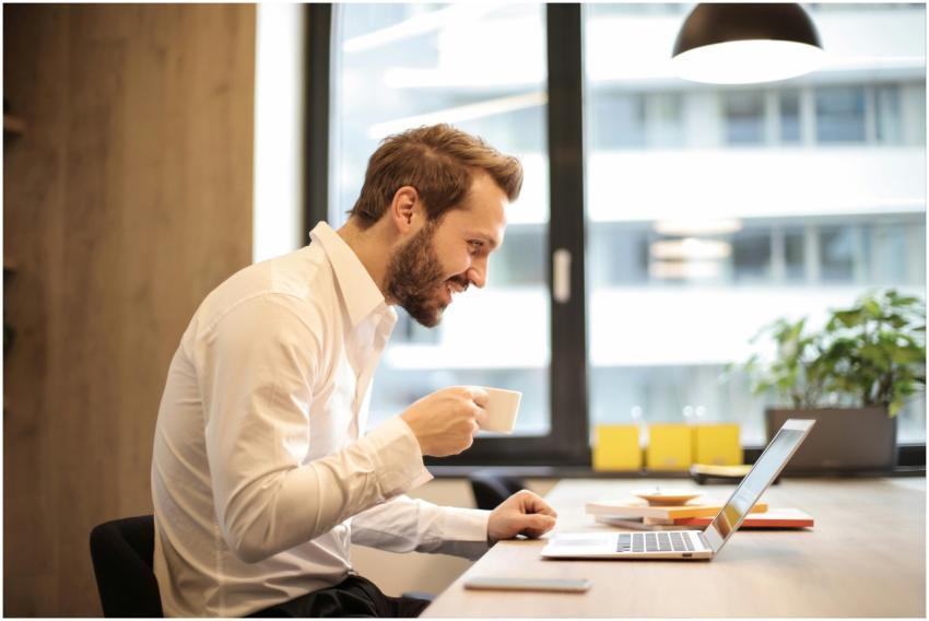 Man in office with coffee, smiling while working a