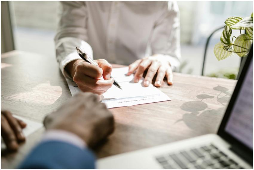 Close-up of people signing a document at a desk, h