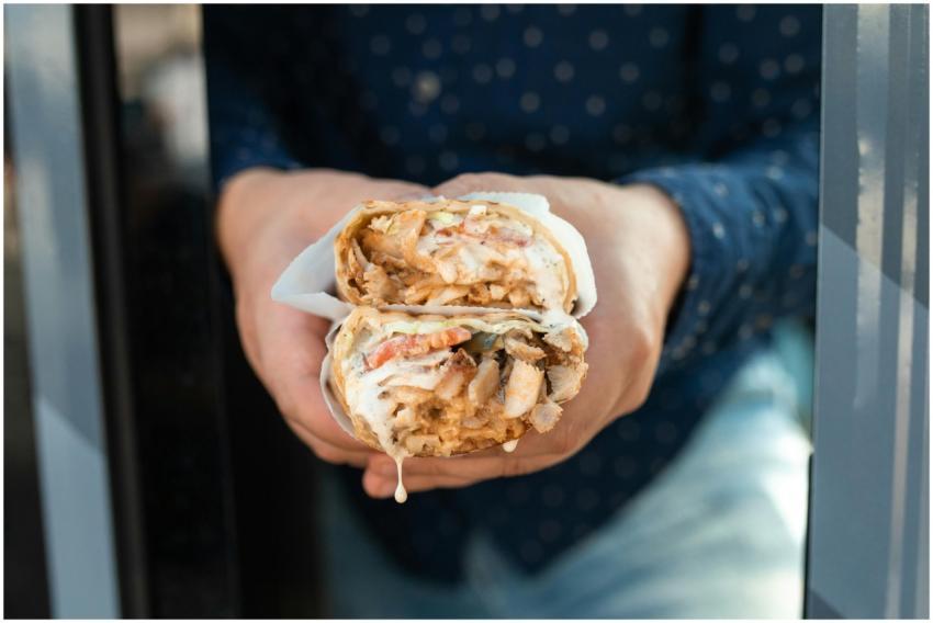 Delicious chicken shawarma held by hand, wrapped w